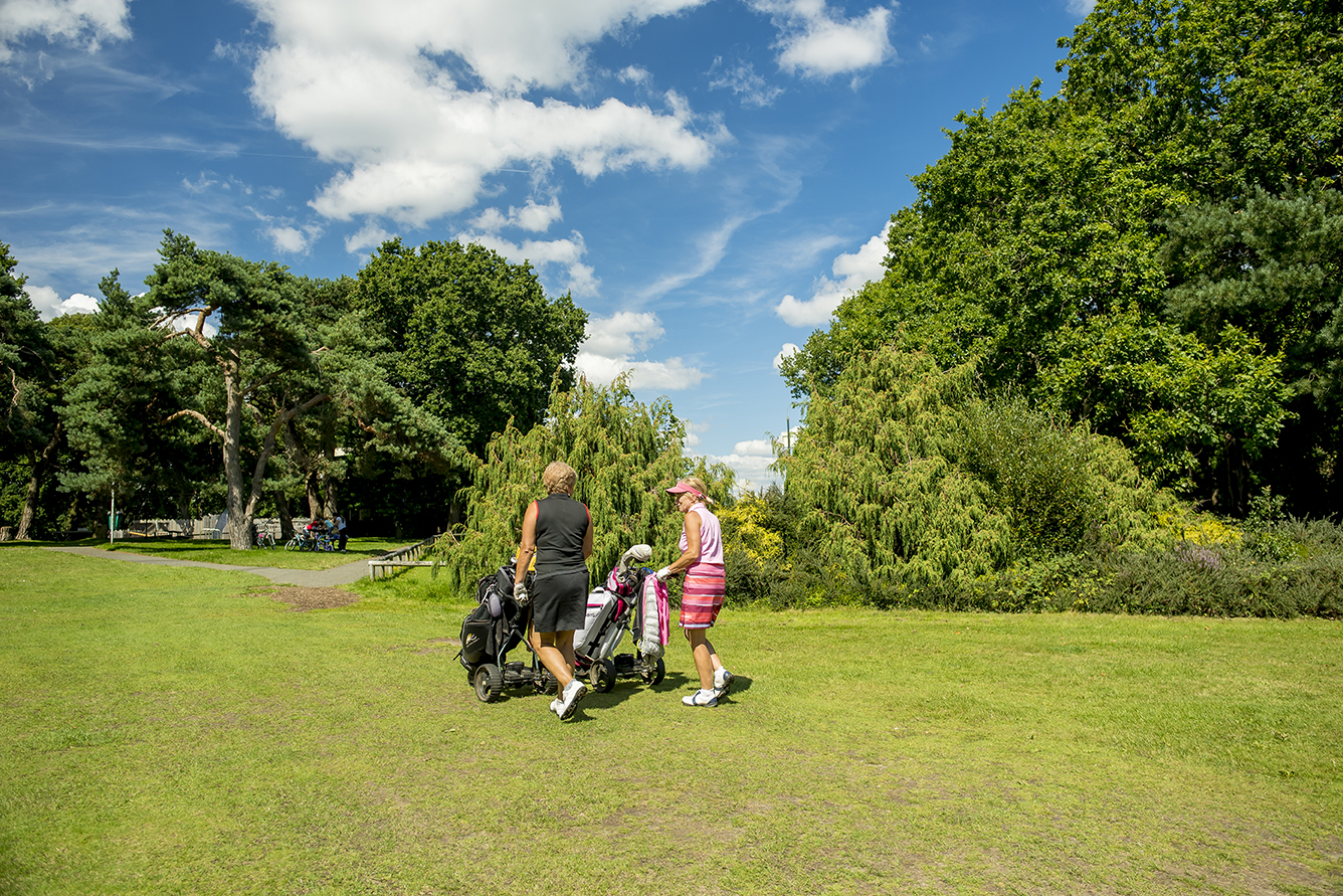 People pushing carts on the golf course