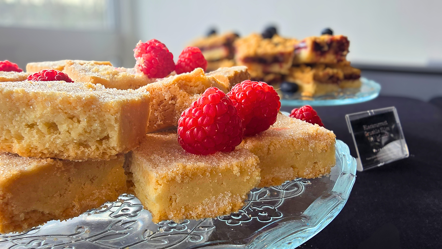 Slices of cake topped with raspberries on a glass plate.